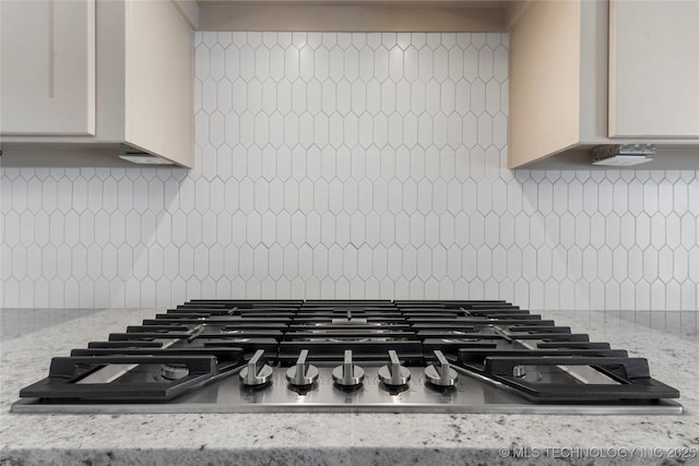 interior details with white cabinetry, stainless steel gas stovetop, and light stone counters