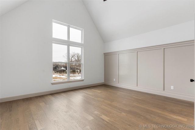 additional living space featuring high vaulted ceiling, wood finished floors, and baseboards