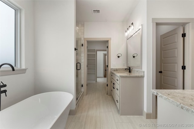 bathroom with a freestanding tub, vanity, visible vents, a spacious closet, and a shower stall