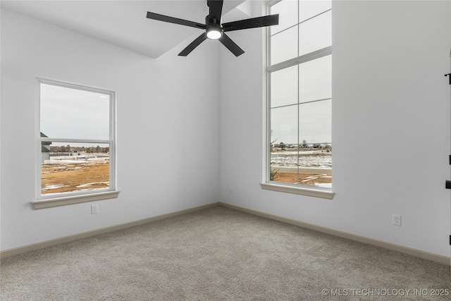 carpeted spare room featuring a ceiling fan and baseboards