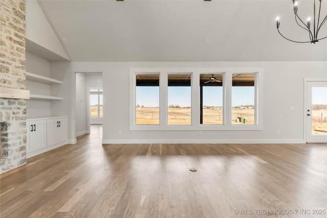 unfurnished living room with lofted ceiling, built in features, an inviting chandelier, and light wood-type flooring