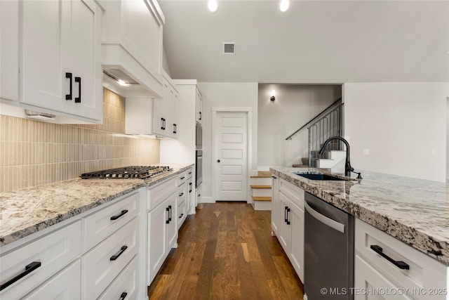 kitchen with sink, appliances with stainless steel finishes, white cabinetry, dark hardwood / wood-style floors, and light stone counters