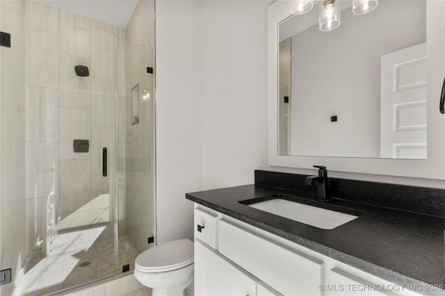 bathroom featuring vanity, toilet, and a shower with shower door