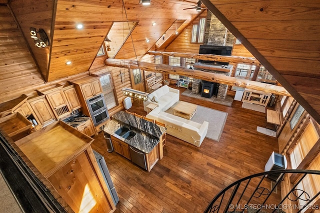 living room with dark hardwood / wood-style floors, high vaulted ceiling, log walls, ceiling fan, and wood ceiling