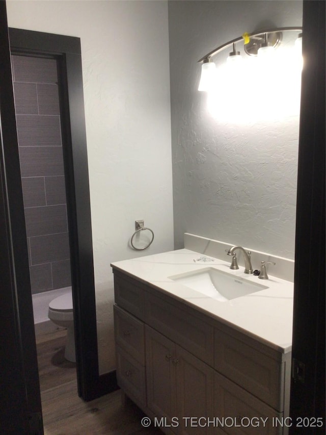 bathroom with toilet, vanity, and wood-type flooring