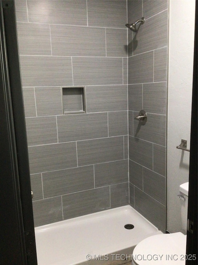 bathroom featuring toilet and a tile shower