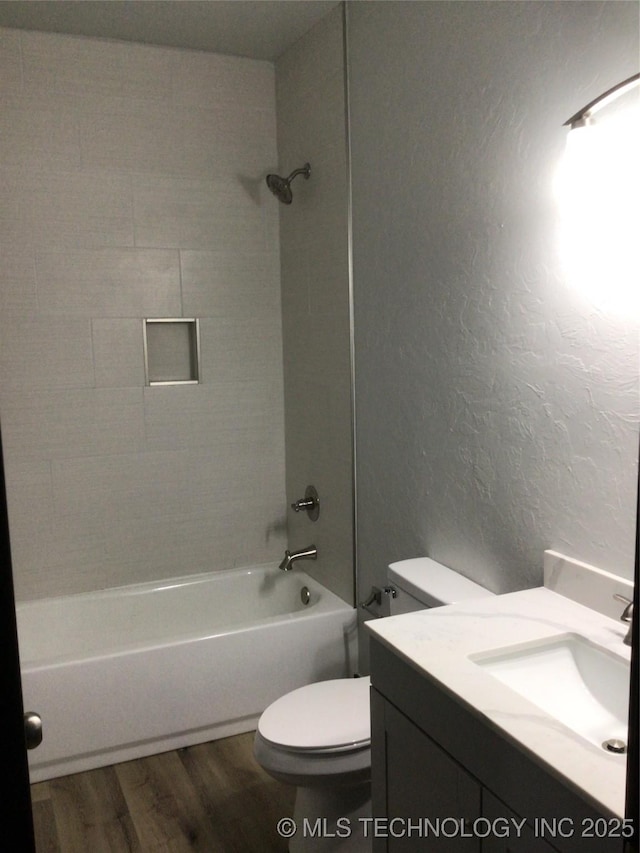 full bathroom featuring toilet, tiled shower / bath, wood-type flooring, and vanity