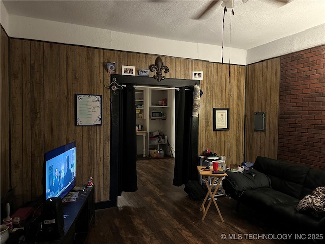 119 S Arkansas St, Caddo, OK 74729 - living area featuring a ceiling fan, wooden walls, and dark wood finished floors