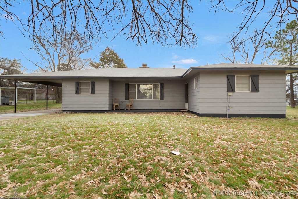 back of property with a yard and a carport