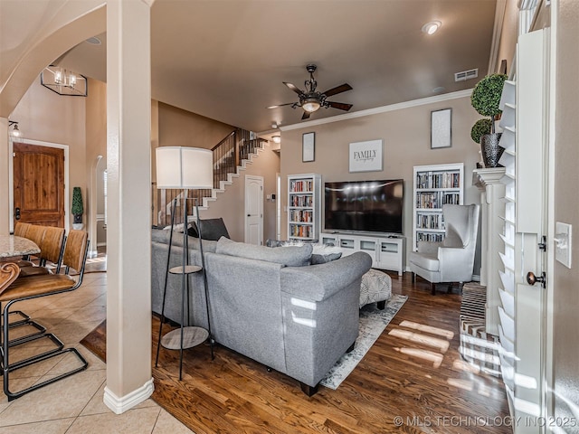 living room featuring ornamental molding, ceiling fan with notable chandelier, and hardwood / wood-style flooring