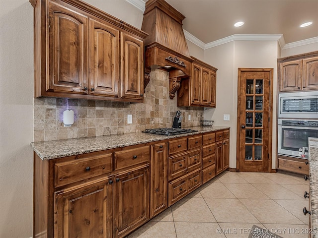 kitchen featuring light stone counters, light tile patterned floors, appliances with stainless steel finishes, and crown molding