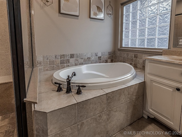 bathroom featuring vanity and tiled tub