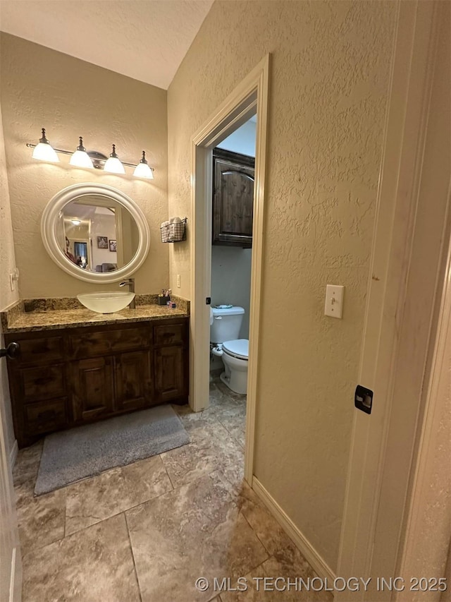 bathroom featuring a textured ceiling, toilet, and vanity