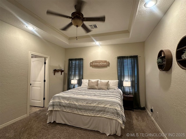 carpeted bedroom featuring ceiling fan and a raised ceiling