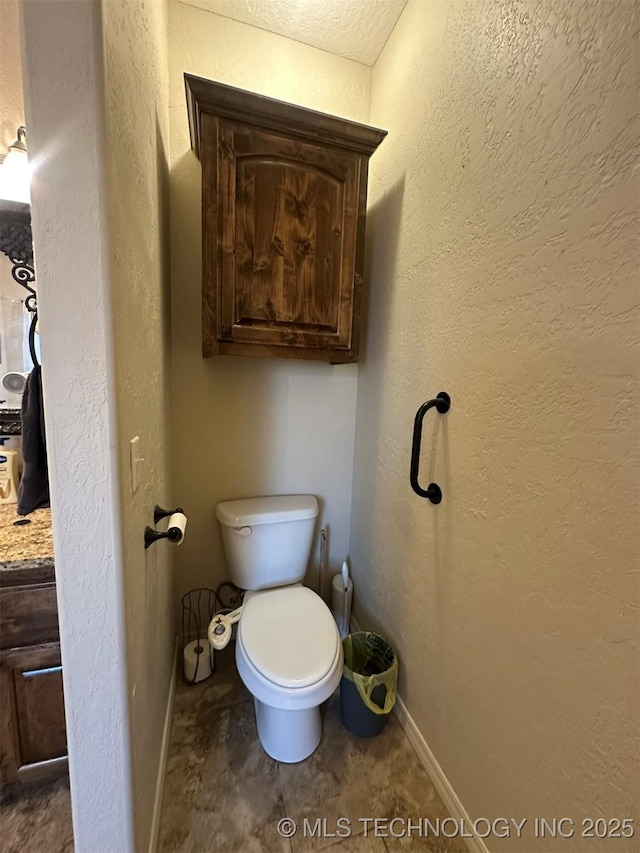 bathroom featuring a textured ceiling, toilet, and vanity