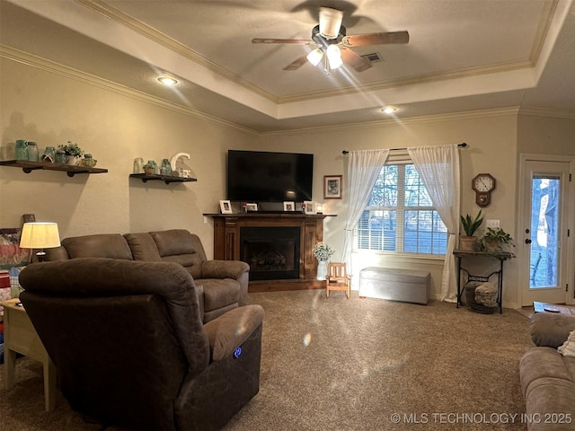 living room featuring ceiling fan, crown molding, carpet floors, and a raised ceiling