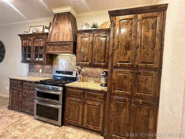 kitchen with double oven range, premium range hood, ornamental molding, and dark brown cabinets