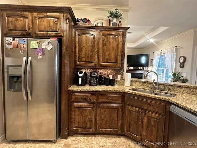 kitchen with a raised ceiling, sink, dark brown cabinetry, light stone countertops, and stainless steel appliances