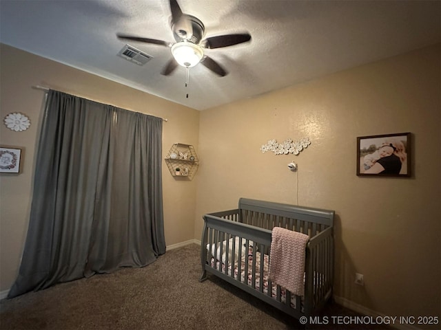 bedroom with a textured ceiling, ceiling fan, carpet flooring, and a nursery area