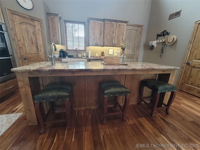 kitchen with a kitchen island, double oven, dark hardwood / wood-style flooring, and sink