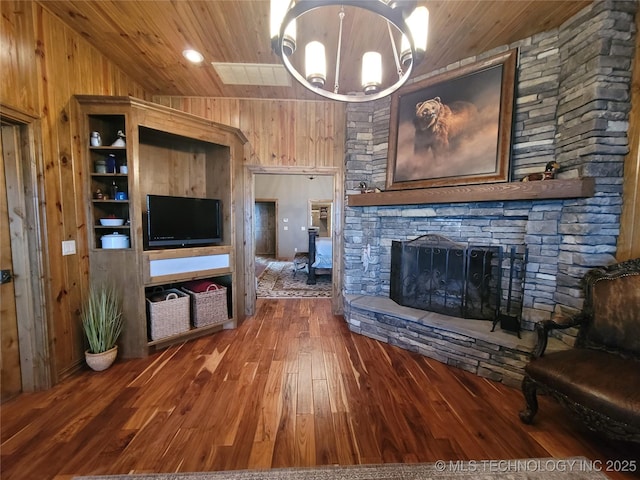 unfurnished living room with wood-type flooring, wood walls, a stone fireplace, and vaulted ceiling