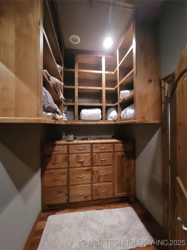 walk in closet with light hardwood / wood-style floors