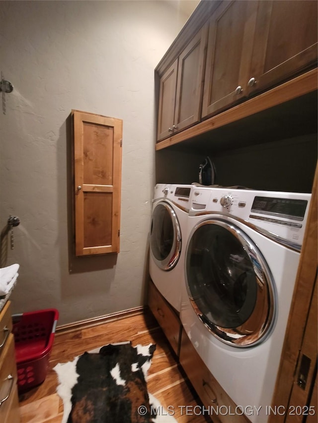 laundry area featuring light wood-type flooring, cabinets, and washing machine and clothes dryer