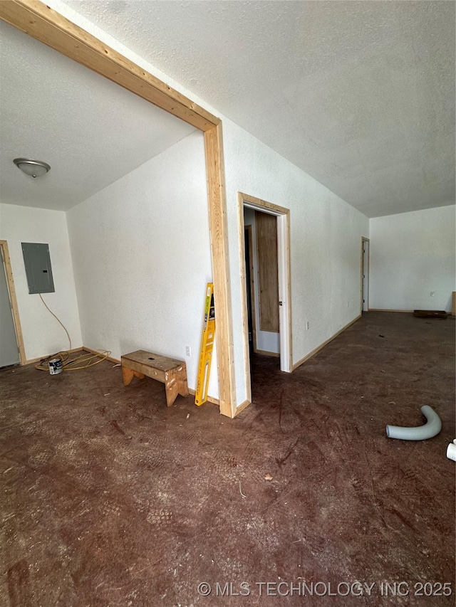 interior space featuring dark colored carpet, a textured ceiling, and electric panel