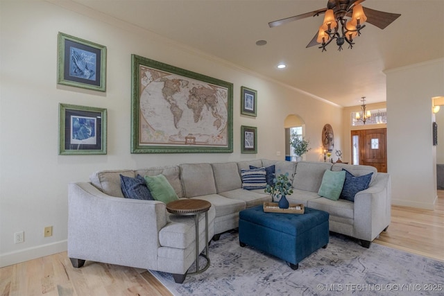 living room with ornamental molding, ceiling fan with notable chandelier, and wood-type flooring