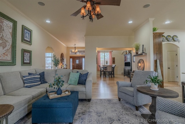 living room featuring ceiling fan with notable chandelier, crown molding, and light wood-type flooring