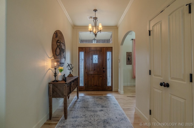 entryway with light wood-type flooring, crown molding, and a chandelier