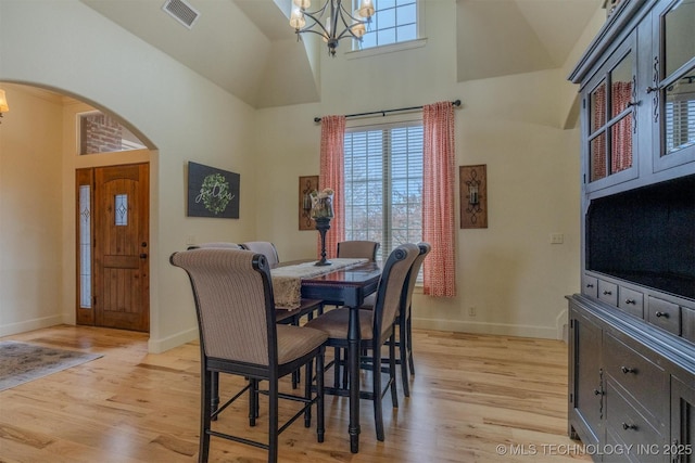 dining area with high vaulted ceiling, a chandelier, and light hardwood / wood-style floors