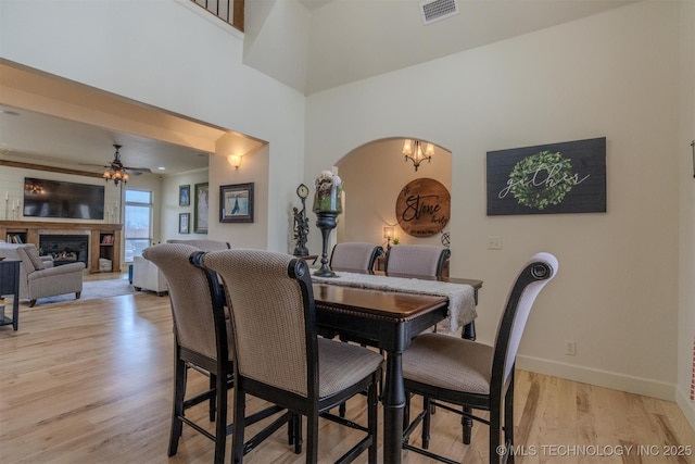 dining room with light hardwood / wood-style floors and ceiling fan with notable chandelier