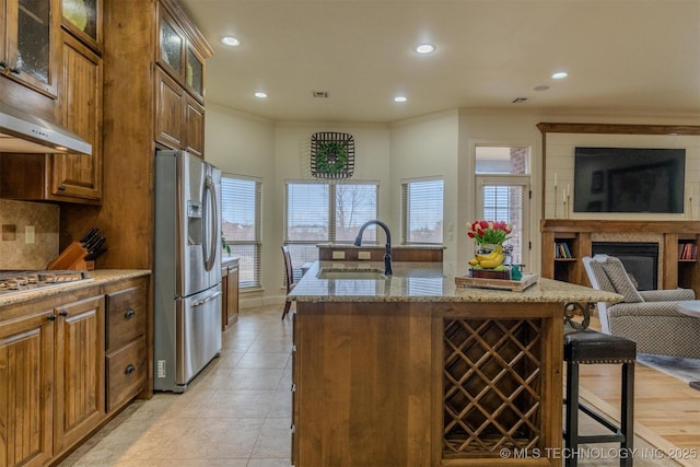 kitchen featuring light stone countertops, stainless steel appliances, sink, backsplash, and a breakfast bar