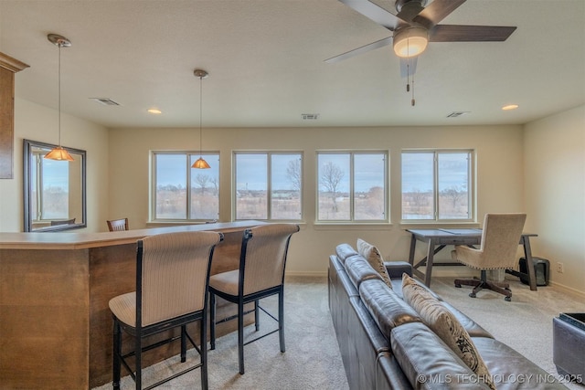 carpeted living room with ceiling fan and bar