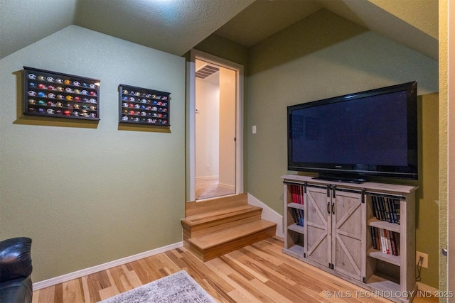 living room with a textured ceiling, lofted ceiling, and wood-type flooring