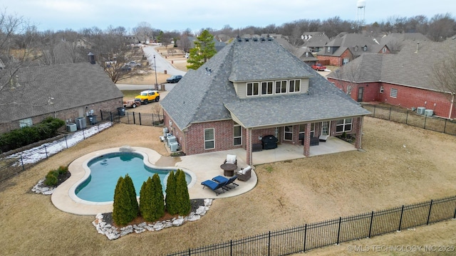 back of property with a fenced in pool, a lawn, and a patio