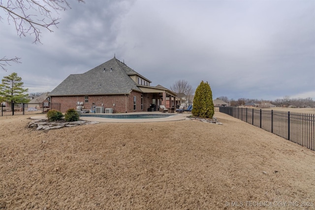 rear view of property featuring a patio and a fenced in pool