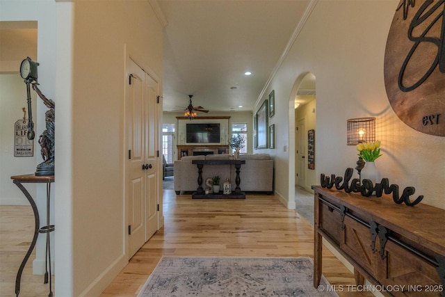 corridor with ornamental molding and light hardwood / wood-style flooring