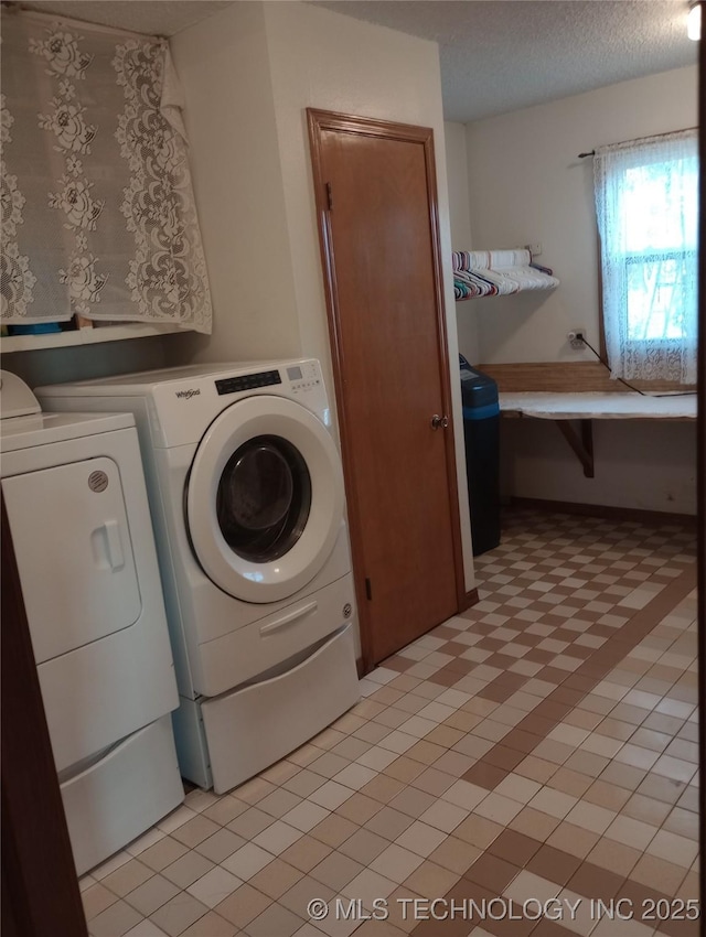 washroom with a textured ceiling and washer and dryer