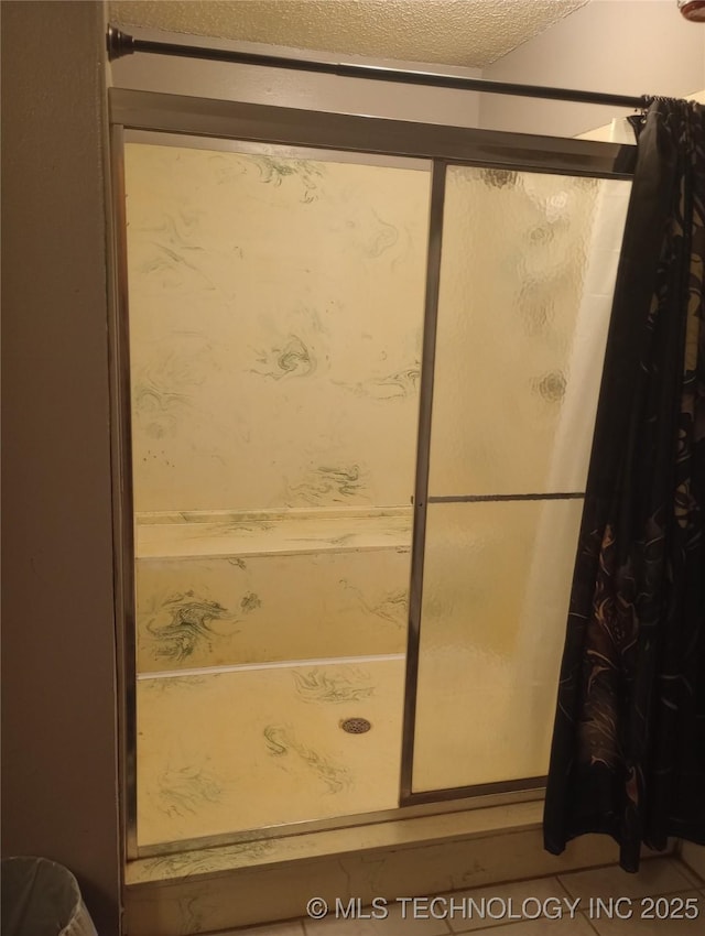 bathroom featuring a textured ceiling, tile patterned floors, and walk in shower