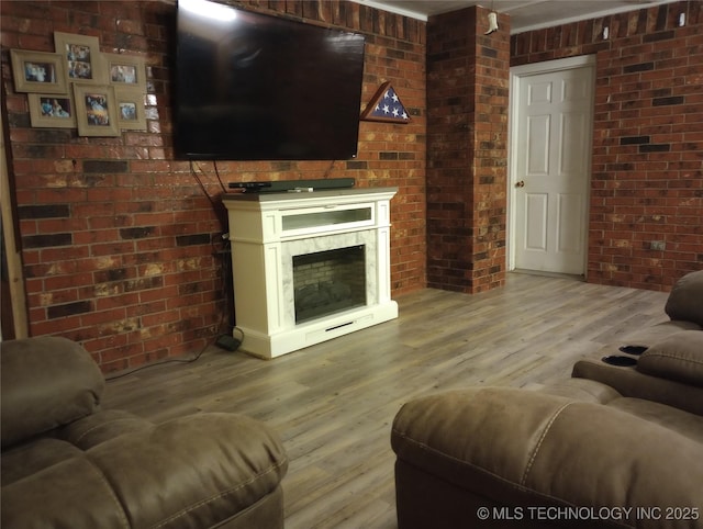 living room with brick wall, ornamental molding, and light hardwood / wood-style flooring