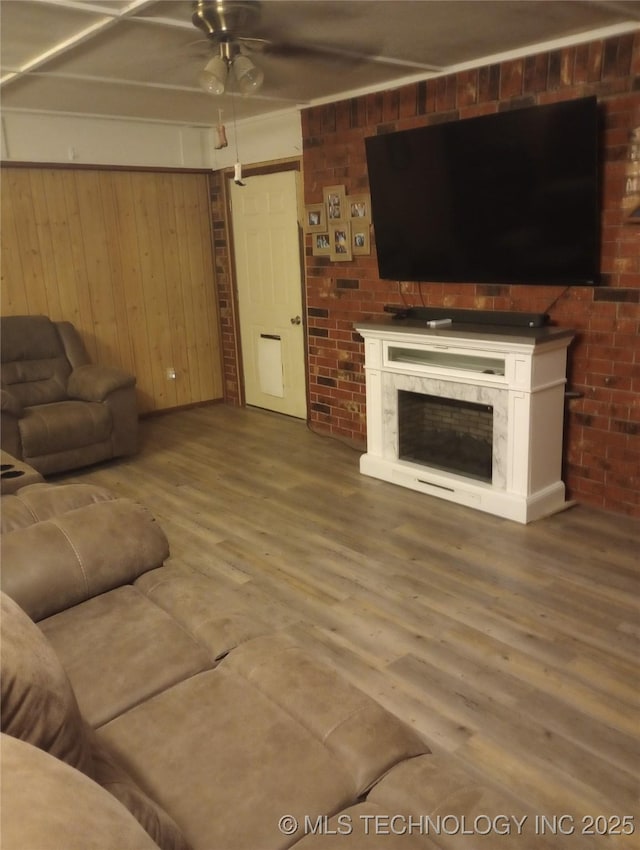 living room featuring ceiling fan, wood-type flooring, and wooden walls