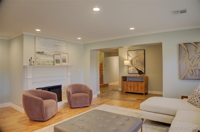 living room with a brick fireplace, hardwood / wood-style floors, and crown molding