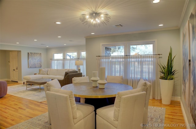 dining space with ornamental molding, light hardwood / wood-style flooring, and a notable chandelier