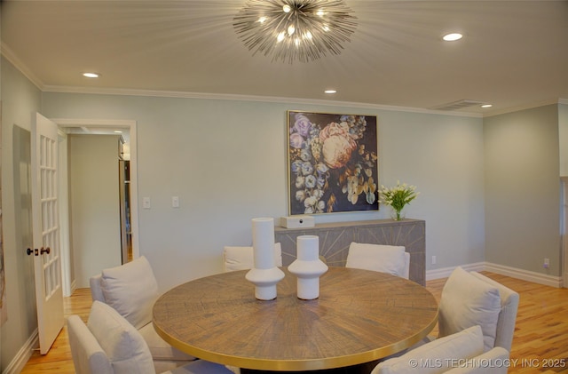 dining area featuring light hardwood / wood-style flooring, ornamental molding, and a chandelier