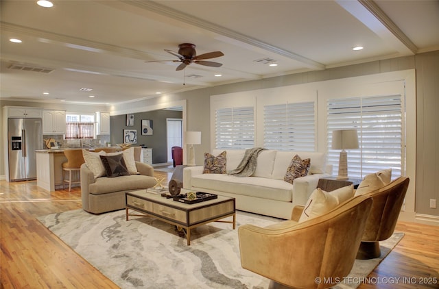 living room with ceiling fan, crown molding, light hardwood / wood-style flooring, and beamed ceiling