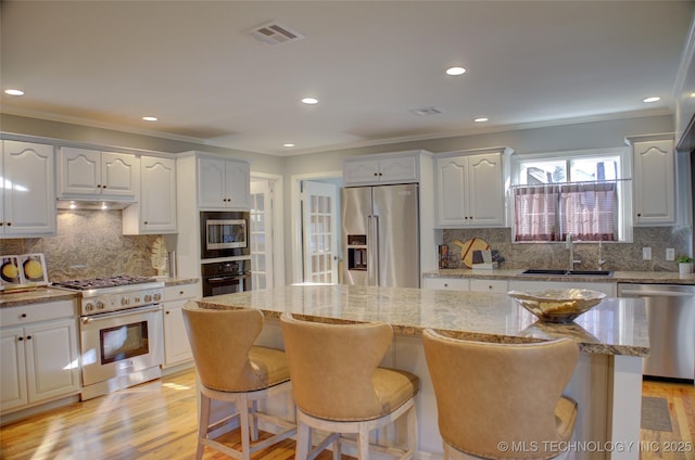 kitchen with sink, white cabinetry, a center island, and high quality appliances