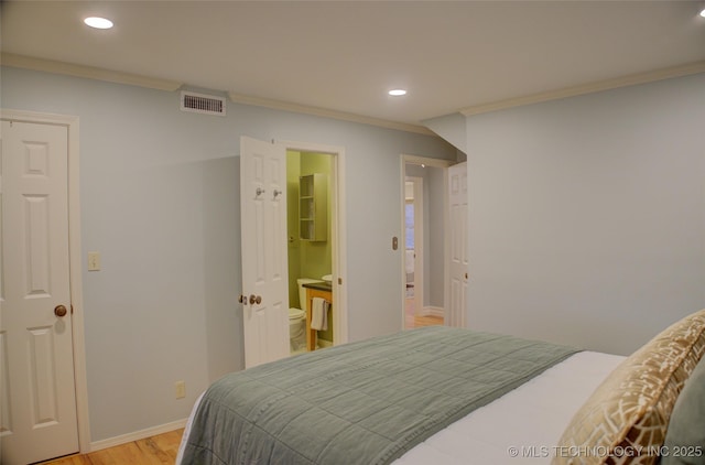 bedroom with connected bathroom, ornamental molding, and light wood-type flooring