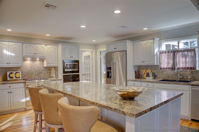 kitchen featuring sink, white cabinetry, stainless steel appliances, and a breakfast bar